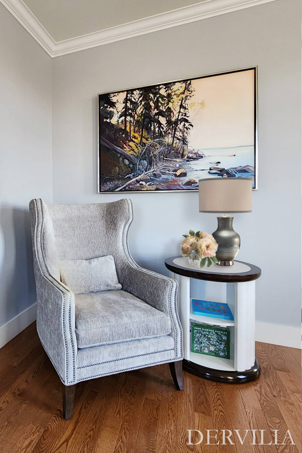Refined interior vignette featuring an upholstered accent chair, ornate framed mirror, landscape artwork, and a styled side table with lamp and florals, expressing Dervilia’s art-led approach to calm, considered spaces.