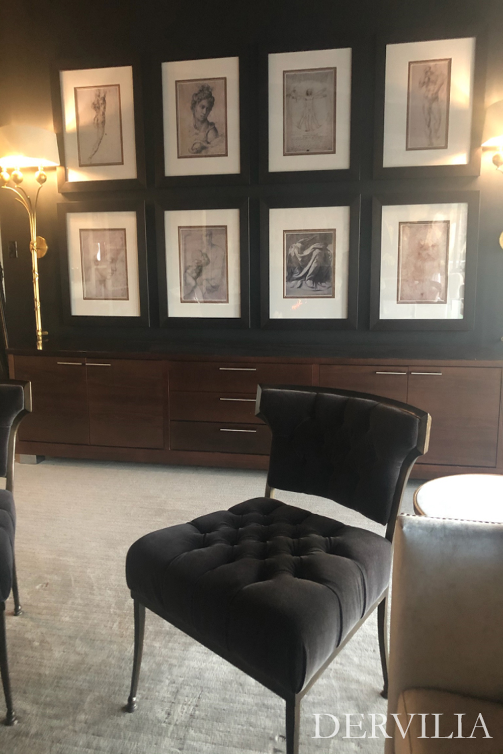 Symmetrical gallery wall featuring a series of framed classical drawings displayed above custom cabinetry, paired with sculptural seating and soft lighting, illustrating Dervilia’s refined approach to art curation and interior balance.