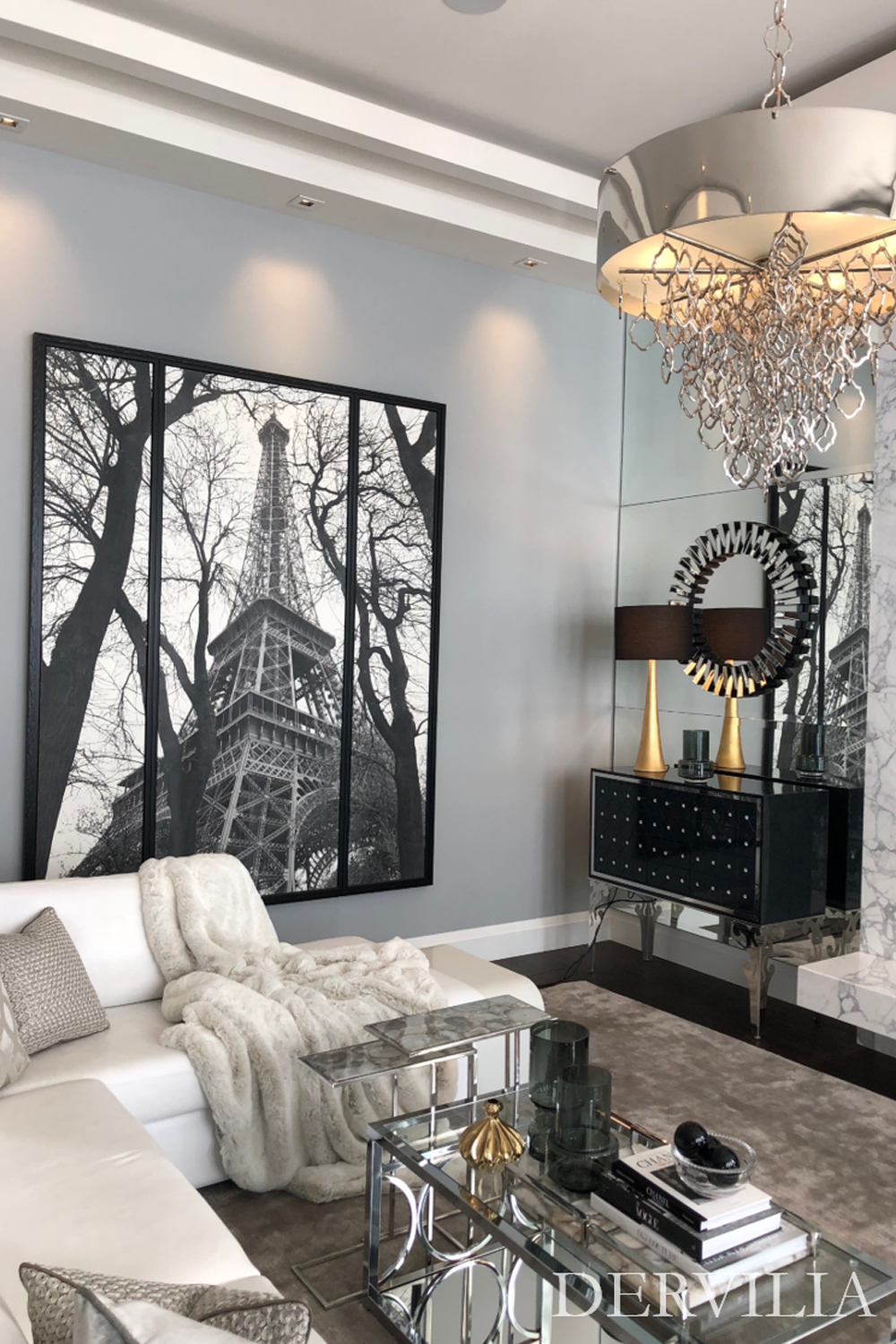 Sophisticated living area styled around large-scale black-and-white artwork, reflective furniture, and a sculptural chandelier, demonstrating Dervilia’s art-first approach to layered, expressive interior design.