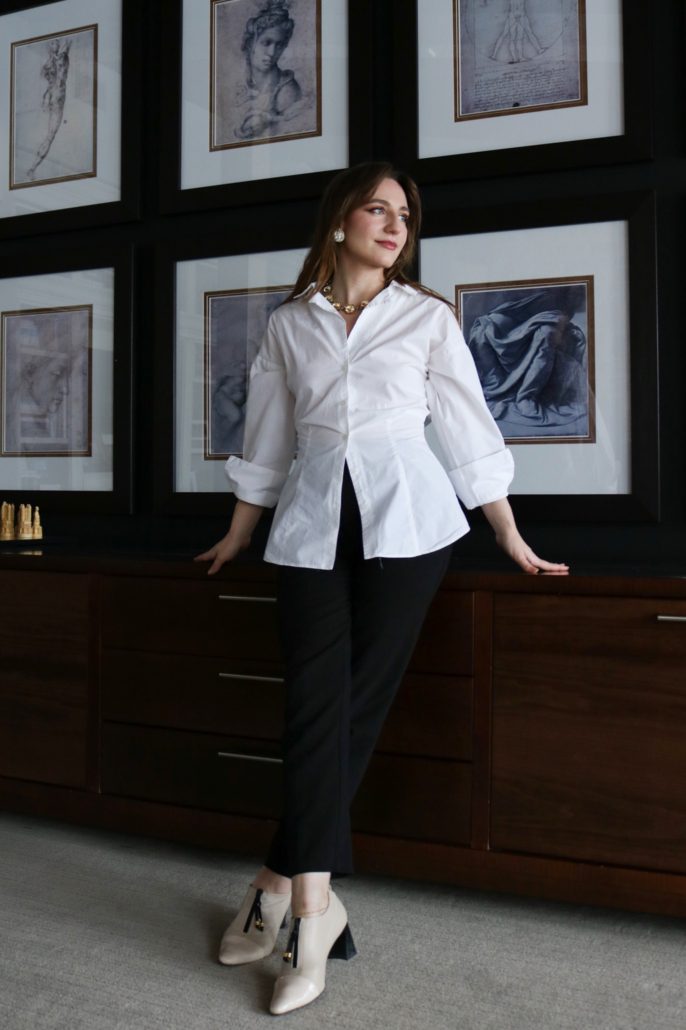 Tiffany Brychun of Dervilia Art + Design standing in a refined interior with framed classical artwork, highlighting her approach to luxurious, detail-driven interior design and architectural harmony.